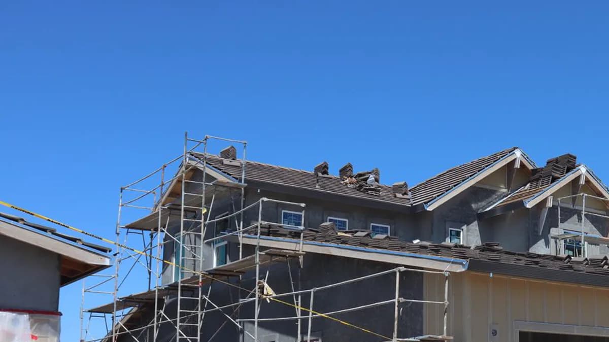 Residential building under construction with scaffolding and roof tile stacks