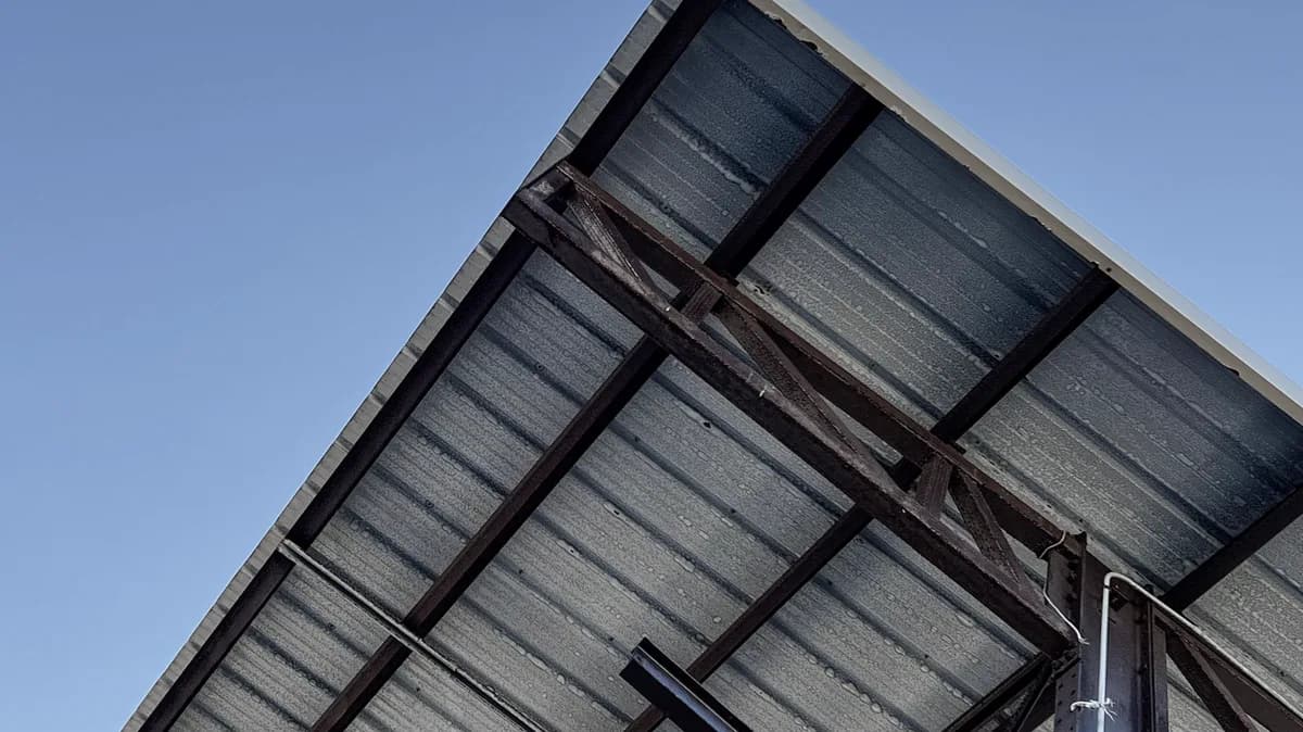 Steel roof framing viewed against a blue sky