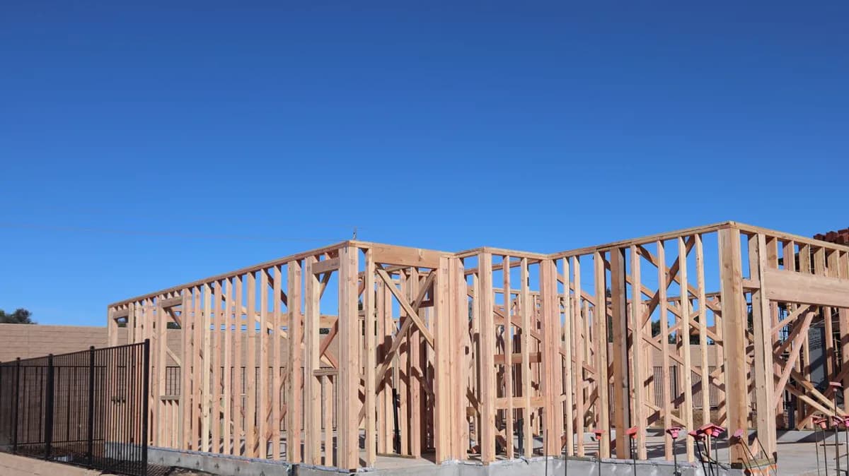 Wood-framed building under construction beneath a clear sky